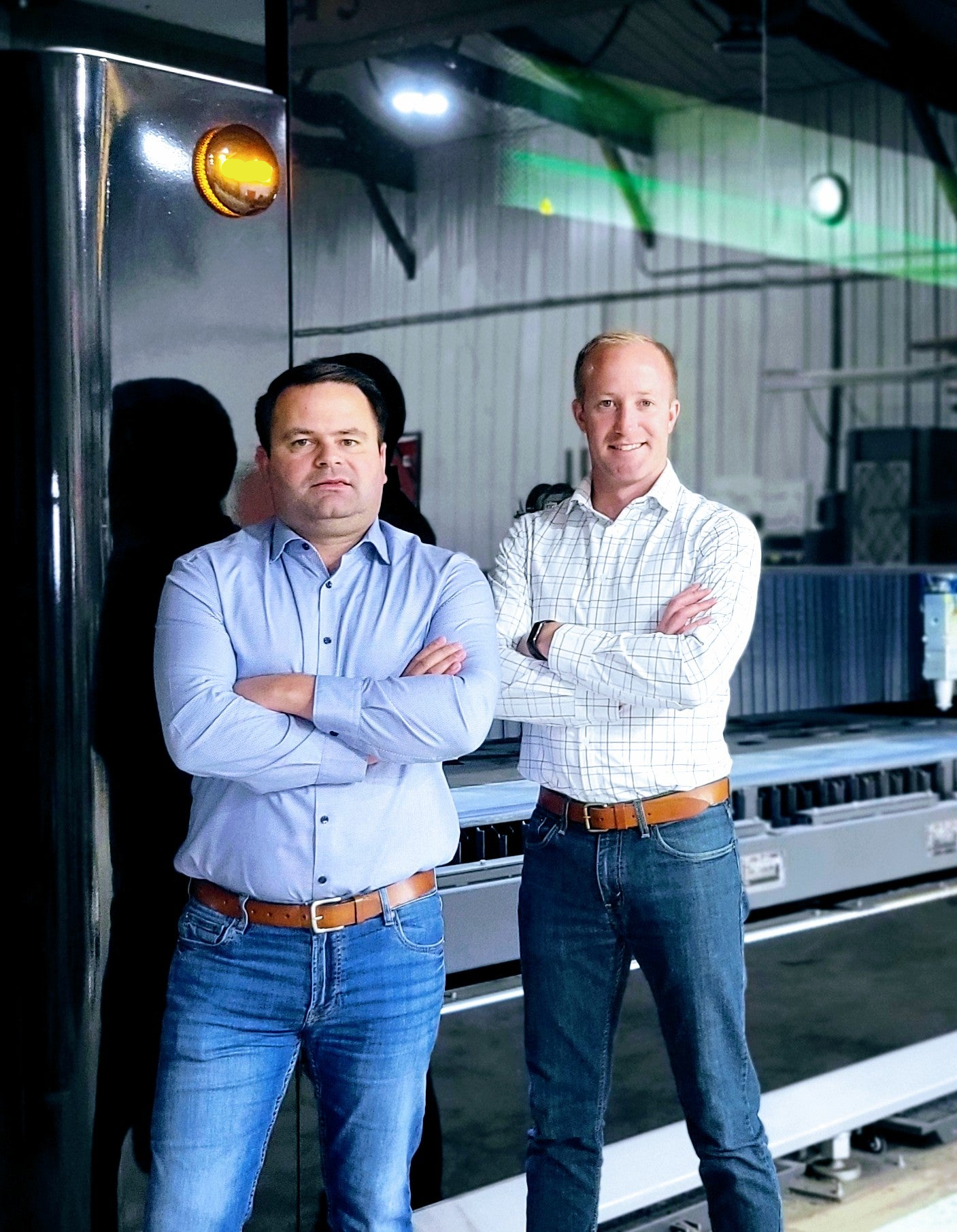 Two men standing in front of industrial machinery in a factory setting